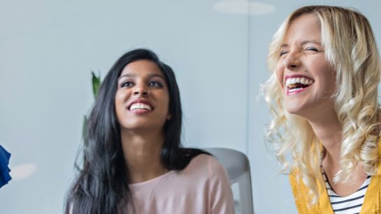 two women smiling at an unknown speaker in a group