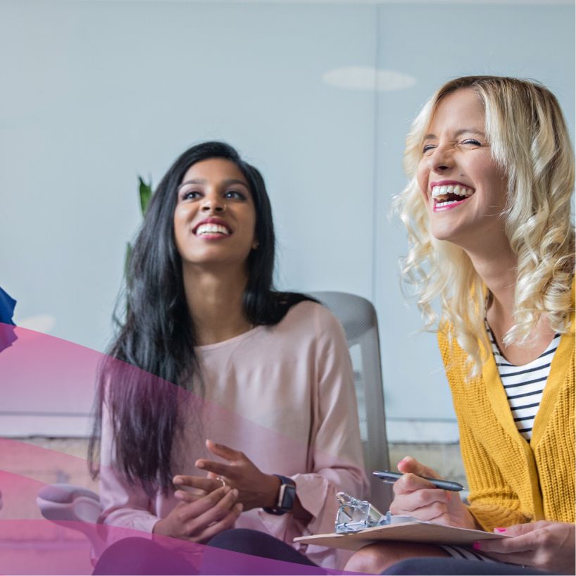 two women smiling at an unknown speaker in a group