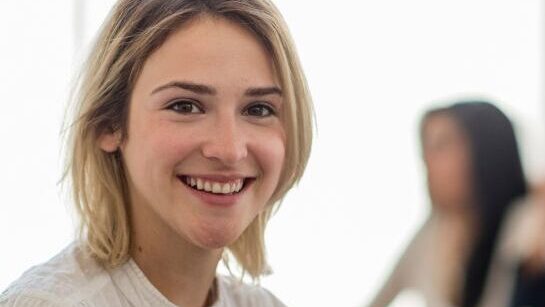 woman smiling at the camera at a desk