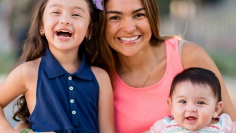 Single mother and two young children smile big at the camera